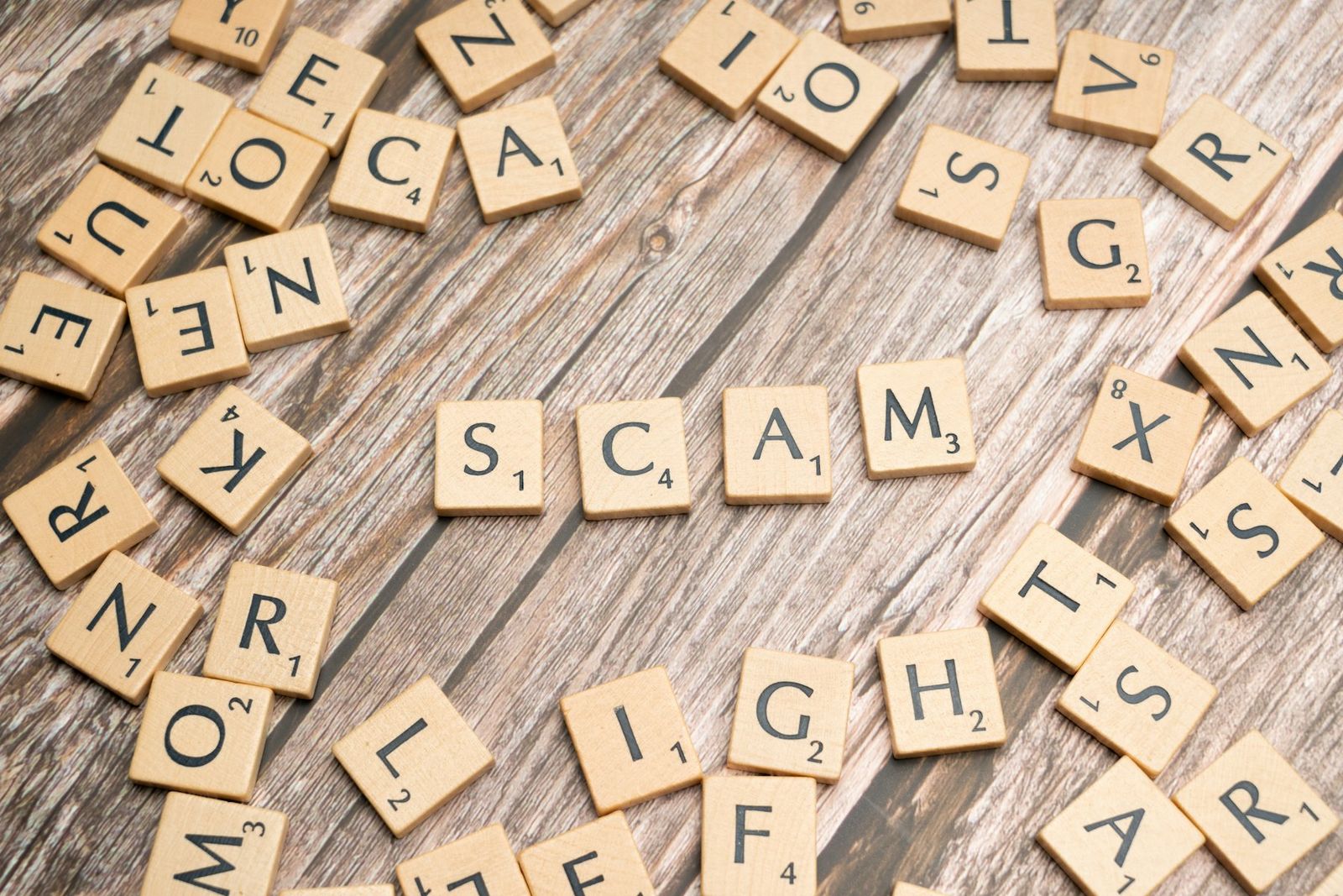 Lettres en bois formant le mot scam sur une table