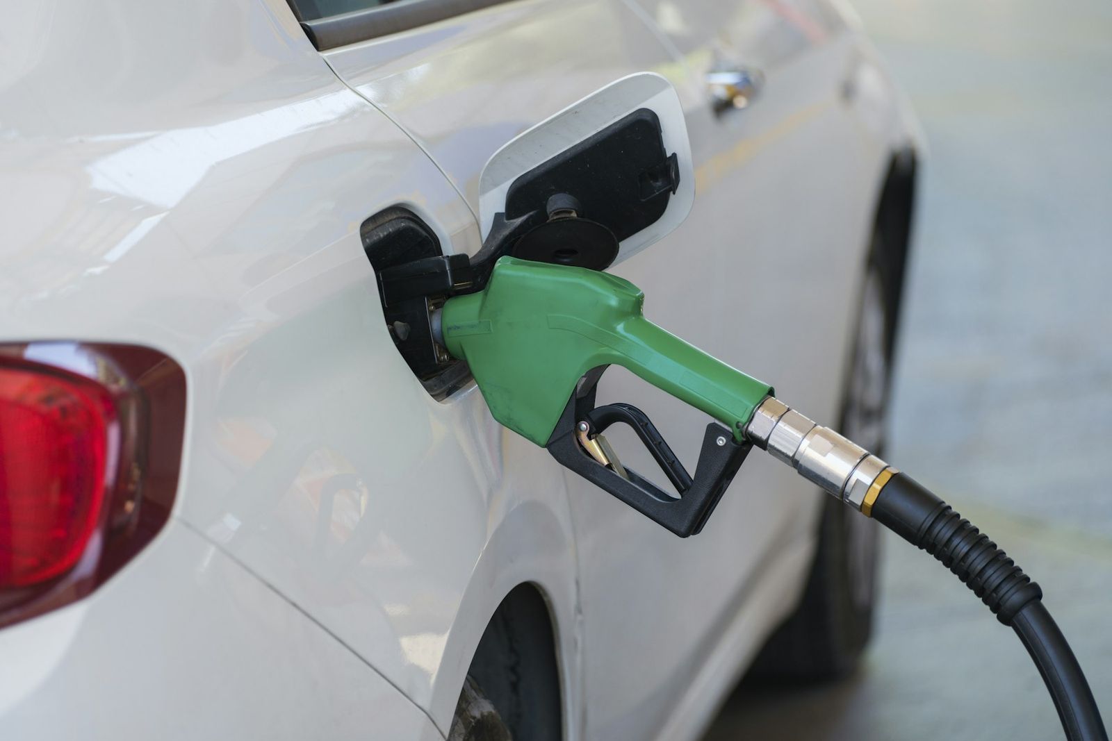 Pistolet de carburant vert dans le réservoir d'une voiture blanche