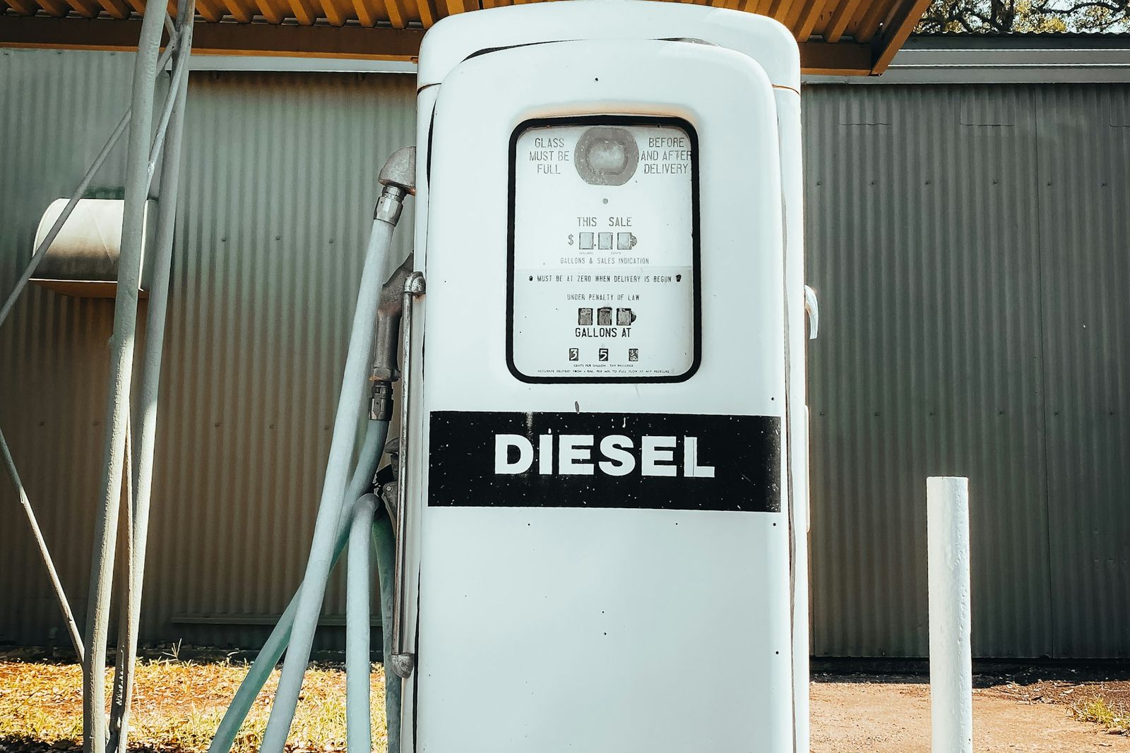 Ancienne pompe à diesel blanche sous un auvent