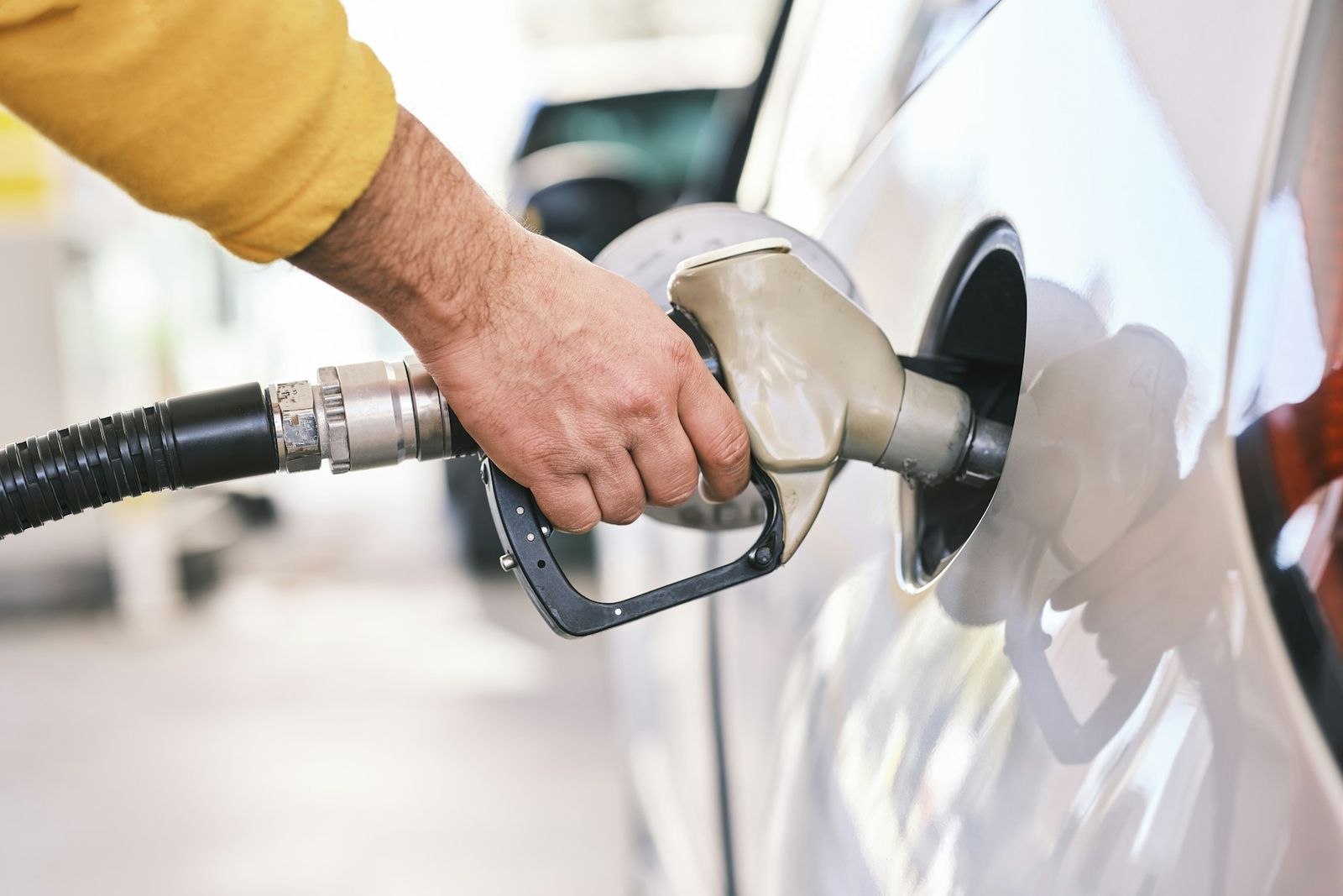 Main tenant un pistolet de carburant dans le réservoir d'une voiture