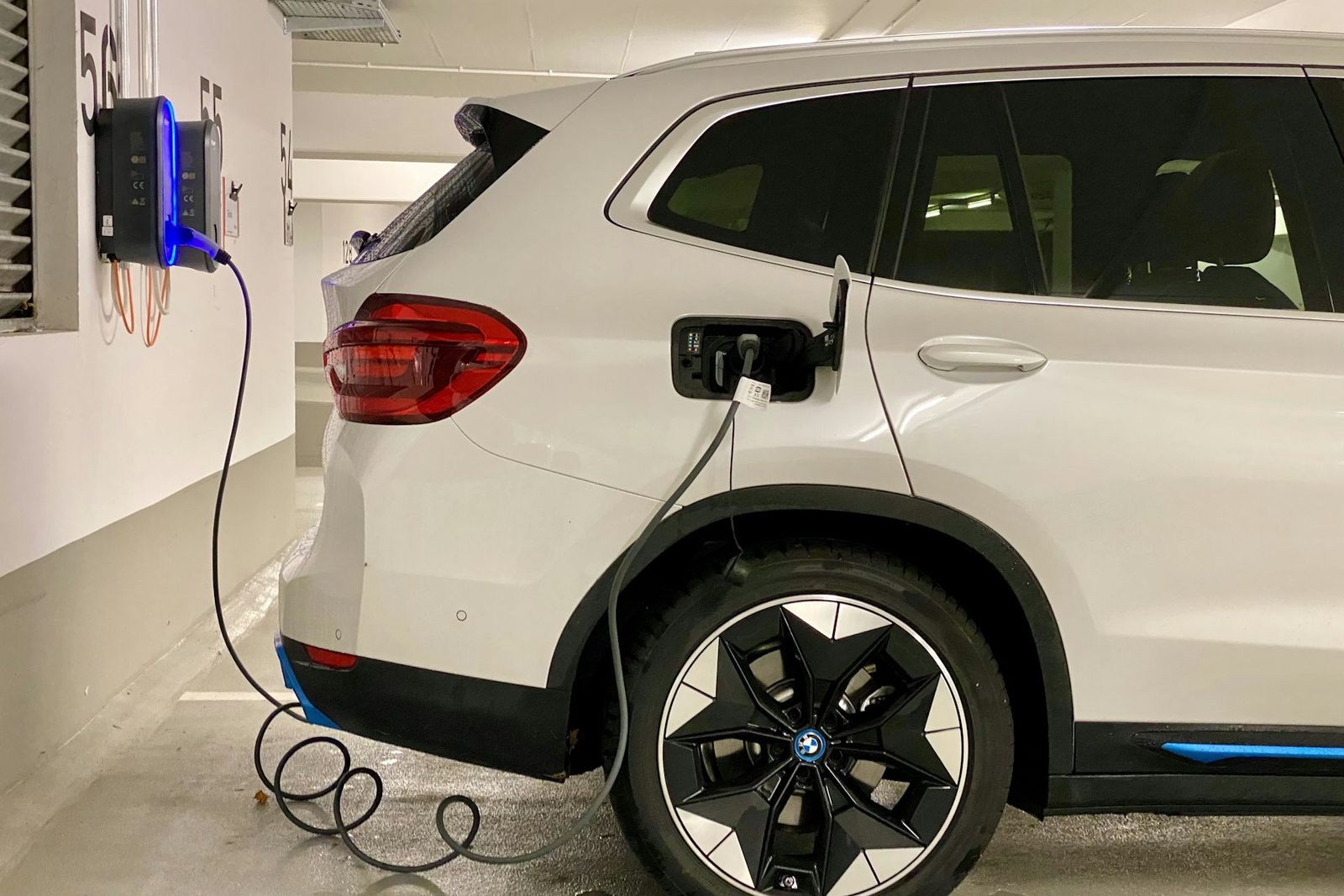 BMW iX3 blanc branché sur une borne dans un parking
