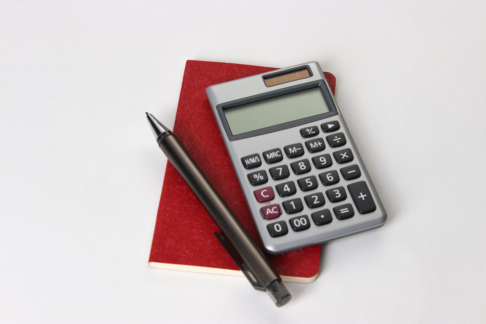 Calculatrice et stylo posés sur un carnet rouge