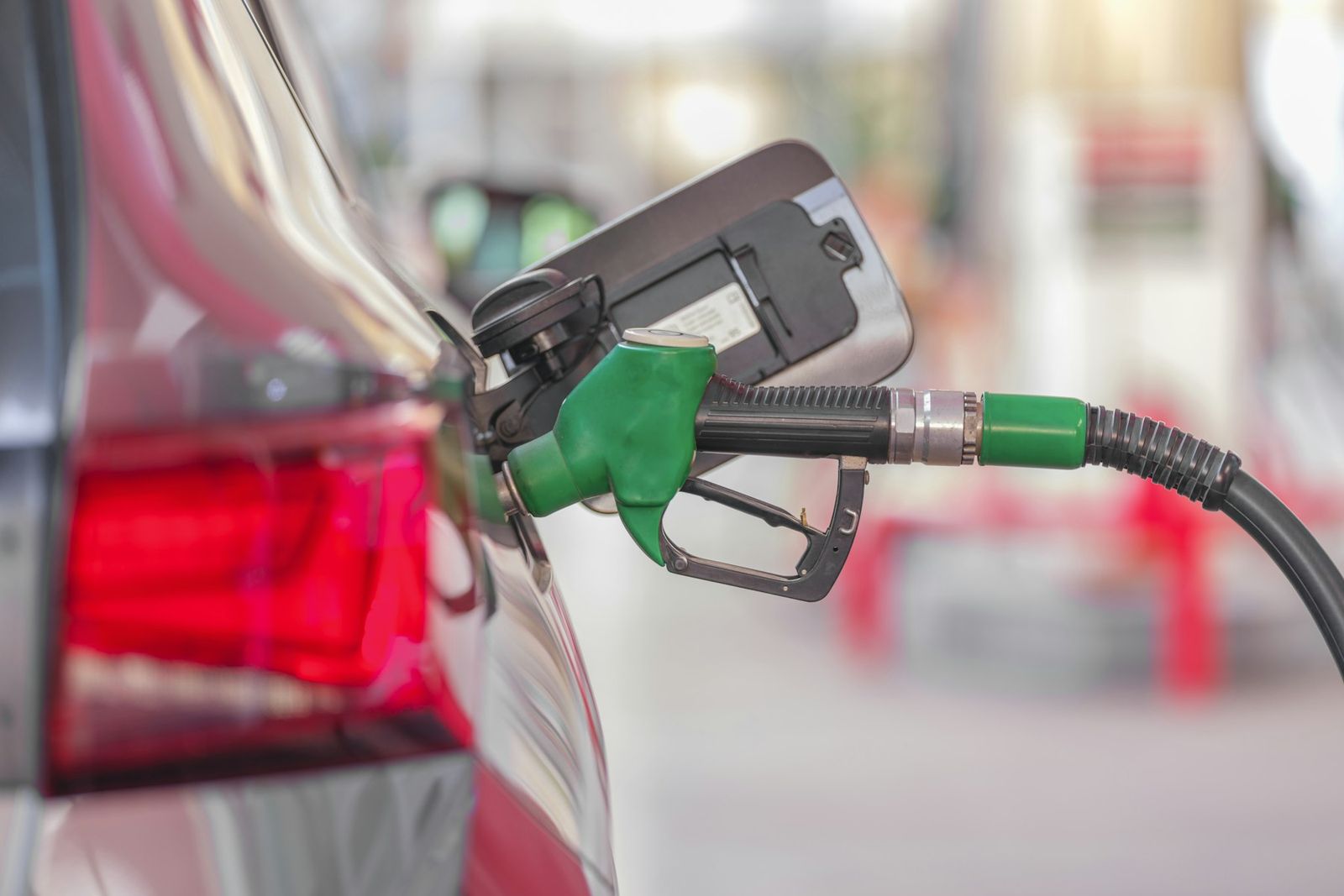 Pistolet de carburant vert engagé dans le réservoir d'une voiture rouge