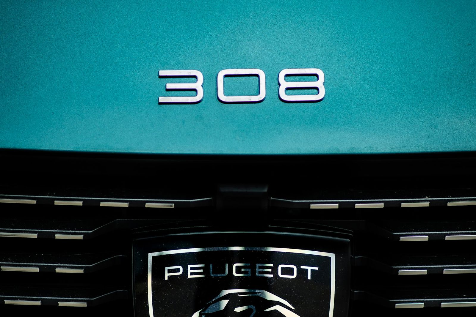 Monogramme 308 et logo Peugeot sur une carrosserie bleu canard