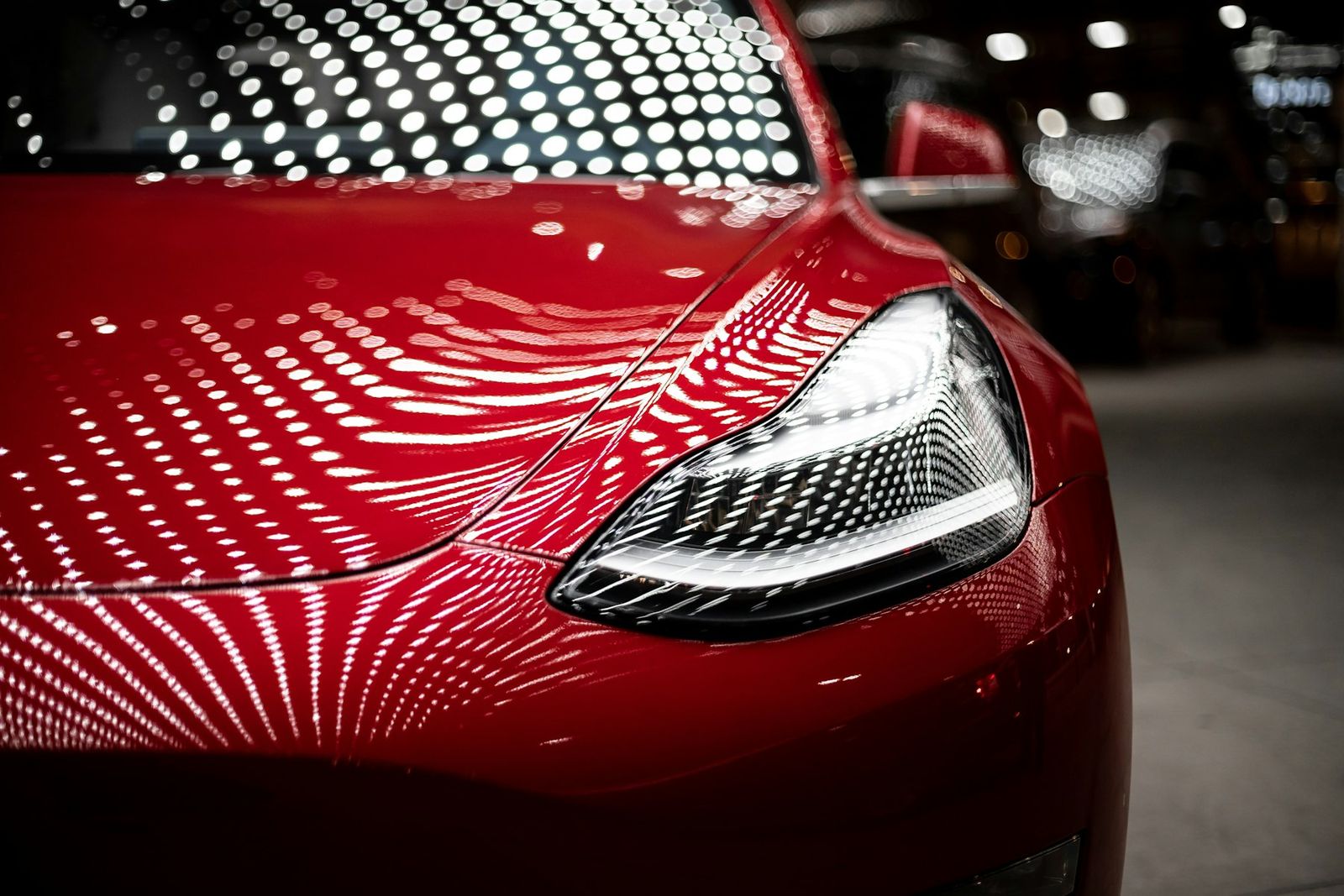 Phare d'une Tesla rouge sous des reflets lumineux