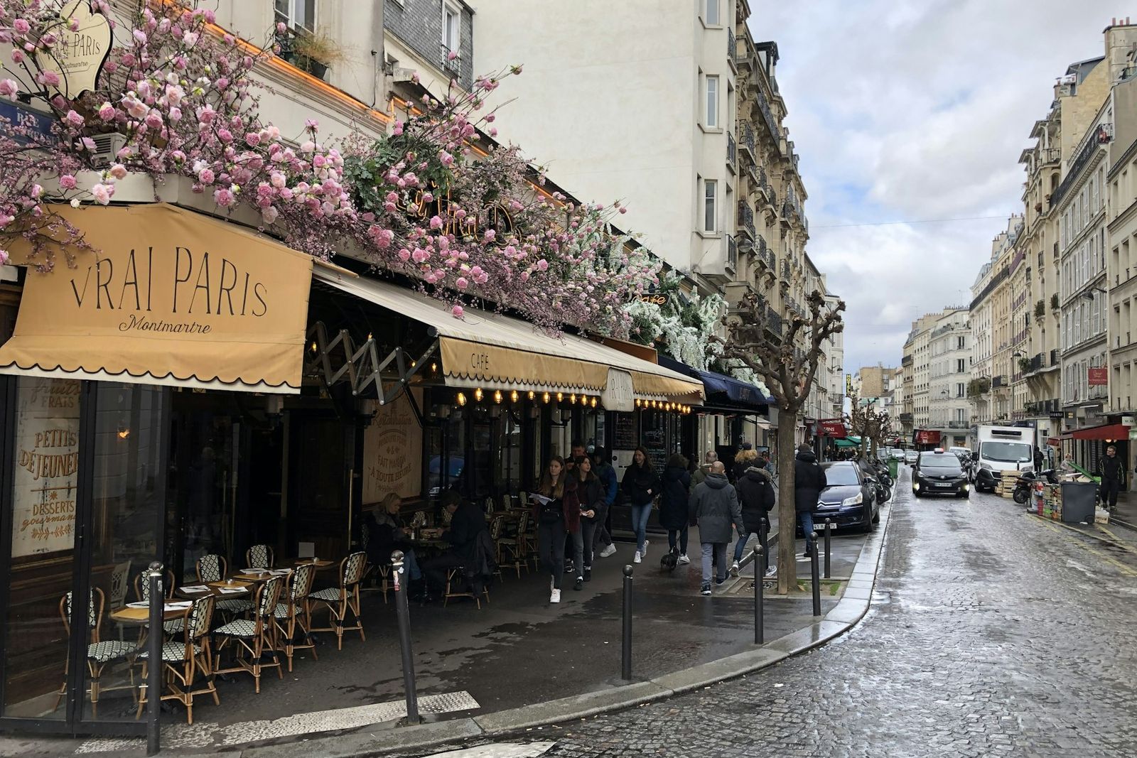 Terrasse de café parisien sur une rue pavée mouillée